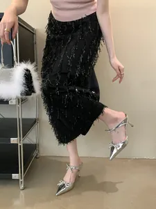 Detail view of silver pointed-toe heels with rhinestone bow and black sequin fringe skirt