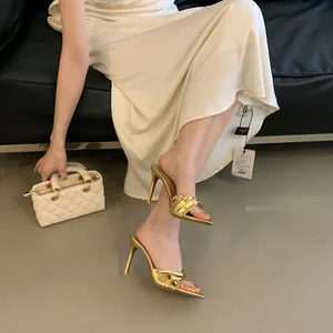 Nahaufnahme eleganter goldener Pantoletten mit spitzer Kappe und stilvoller Knotung