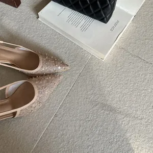 Vista detallada de zapatos de tacón beige con encaje, perlas y punta fina elegante
