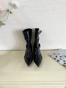 Close-up front view of elegant black pointed-toe short boots with stylish buckle straps