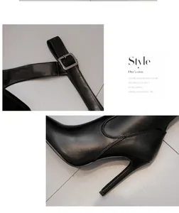 Close-up detail of black leather pointed toe high heel boots showing buckle and stiletto