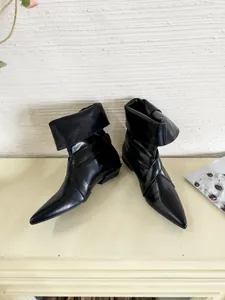 Detail shot of black pointed-toe leather ankle boots with elegant wrap-around design