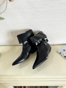 Detailed view of black pointed-toe boots with buckle straps and low block heel