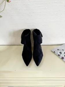 Detail of elegant black pointed-toe short boots with soft suede-like texture