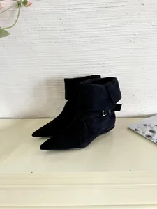 Detailed view of elegant black pointed-toe suede boots with fold-over cuff