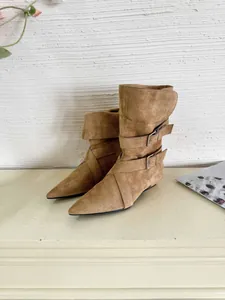 Detailed view of tan suede pointed-toe ankle boots with stylish buckle strap design.