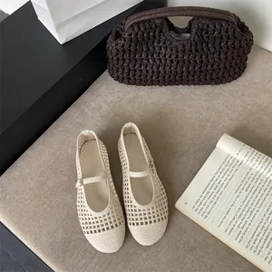 Dettaglio di eleganti ballerine Mary Jane traforate intrecciate color crema su beige