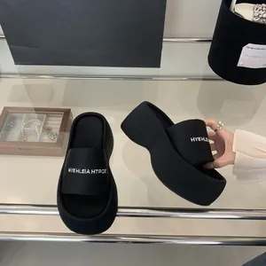 Λεπτομερής κοντινή άποψη μαύρων γυναικείων παντόφλων με πλατφόρμα και λευκό λογότυπο