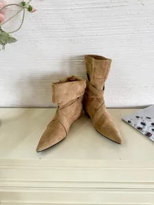 Detailed close-up of stylish tan suede pointed-toe ankle boots featuring a slouchy design.