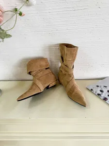 Detailed view of stylish brown suede pointed toe ankle boots with wrap-around straps