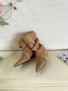 Elegant brown suede pointed-toe ankle boots with decorative buckle straps and low heels.