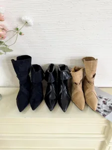 Detailed shot of pointed-toe ankle boots in black and khaki suede and leather finishes.