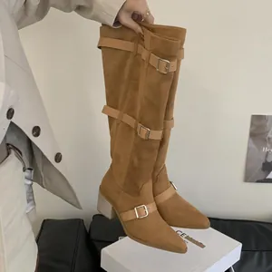 Close-up of camel suede knee-high boots with stylish buckle straps and chunky block heel