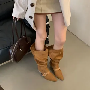 Macro view of brown suede slouchy western boots featuring stylish buckle strap