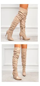 Vue détaillée des cuissardes en cuir verni beige avec bout pointu et talons aiguilles.