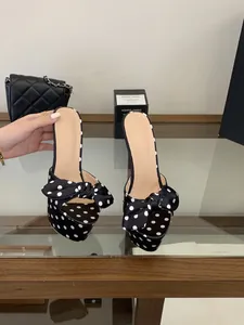 Elegantes sandalias de plataforma con lunares y un gran lazo sobre un estante de vidrio