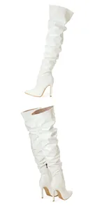 Détail de bottes cuissardes en cuir verni blanc avec talons aiguilles.