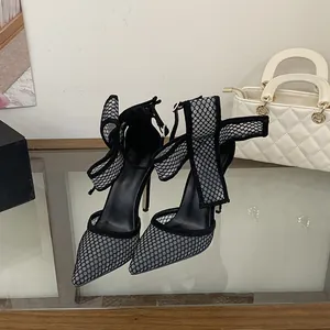 Nahaufnahme von schwarzen Mesh-Stilettos mit Punkten und eleganter Schleife am Knöchel