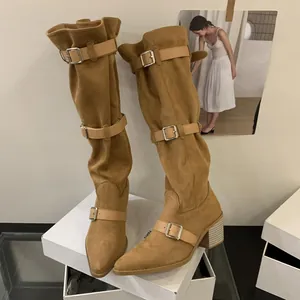 Close-up of camel suede slouchy boots with multiple buckle straps and pointed toe