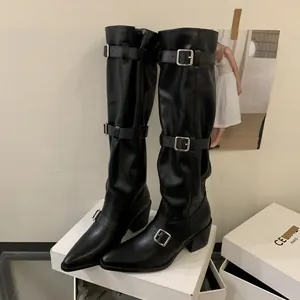 Macro view of black slouchy knee-high boots with silver buckles and pointed toe.