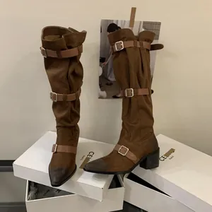 Stylish brown western slouchy knee-high boots with buckle straps on white shoeboxes