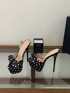 Primer plano de sandalias con plataforma de lunares negros con lazo y tacones muy finos.