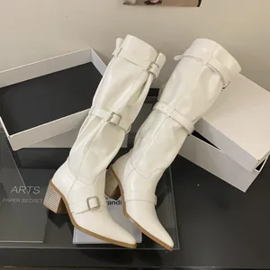 Detailed view of white slouched knee-high boots with pointed toe and silver buckles