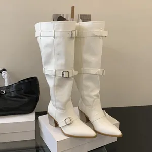 Detailed side view of white pointed-toe knee-high boots featuring stylish buckle straps.