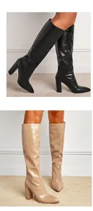Macro view of women's pointed toe chunky heel tall boots with realistic crocodile texture.
