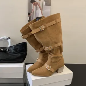 Detail of brown suede slouchy knee-high boots featuring pointed toe and buckle straps