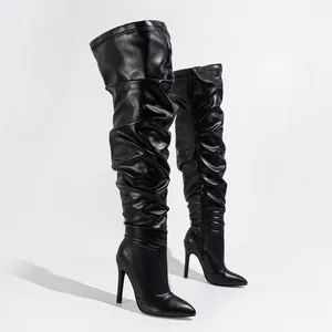 Close-up detail of black slouchy over-the-knee stiletto boots with elegant pointed toe