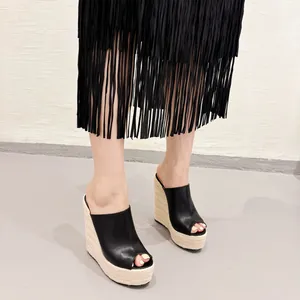 Vue détaillée de sandales compensées noires à bout ouvert portées avec jupe à franges