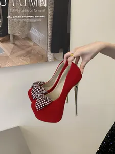 Detail view of red platform stiletto pumps with elegant rhinestone bow accents.