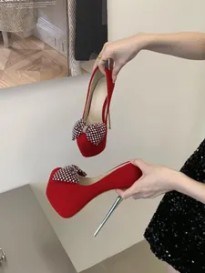 Detailed close-up of red platform heels featuring a large rhinestone bow embellishment
