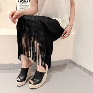 Détail de mules compensées à plateforme en cuir noir avec talon espadrille.