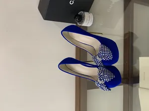 Detail of royal blue platform heels with a sparkling rhinestone bow ornament.