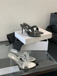 Detailansicht eleganter schwarzer und silberner Sandaletten mit transparenten Trägern.