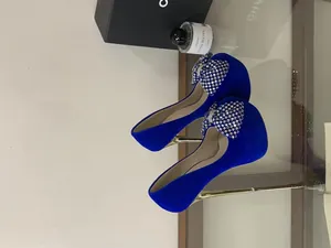 Detailed view of luxury blue velvet platform heels with a sparkling rhinestone bow