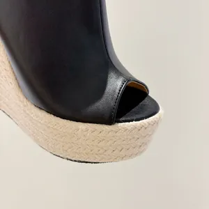 Gros plan de sandales à talons compensés en cuir noir et jute