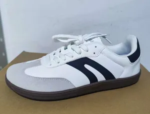 Vista laterale di sneakers bianche in stile tedesco con strisce nere e suola in gomma
