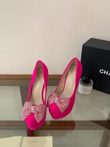 Close-up detail of hot pink platform high heels featuring a sparkling rhinestone bow.
