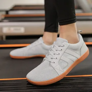 Breathable grey wide toe barefoot sneakers for men and women in a modern gym setting