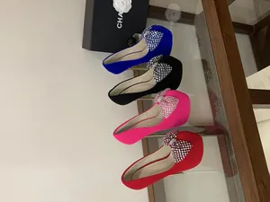 Detail of high platform pumps featuring sparkling rhinestone bows in multiple colors.
