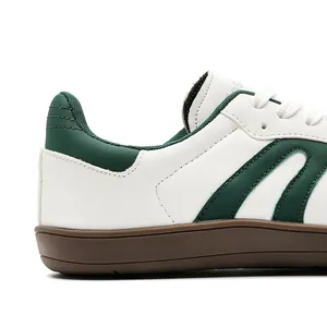 Primo piano delle sneaker GAT in pelle bianco-verde con suola in gomma marrone.
