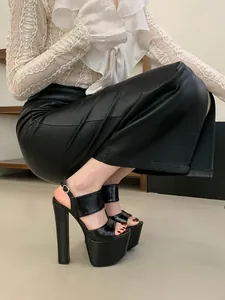 Close-up of black ultra-high platform sandals with chunky heels and ankle straps.