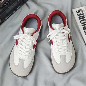 Vista dall'alto di sneakers bianche stile tedesco con accenti rossi e punta larga comoda.