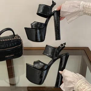 Macro view of black patent leather high platform sandals with sturdy block heels.
