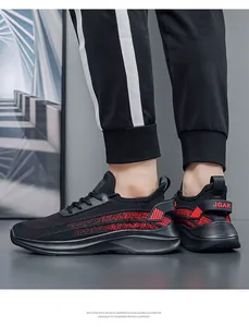 Detail view of black fly-knit sneakers with red accents worn with joggers
