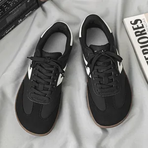 Dettaglio di sneaker GAT nere a punta larga su sfondo di tessuto grigio chiaro