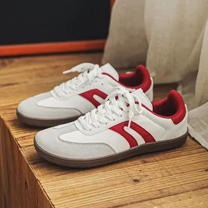 Vista dettagliata delle sneakers stile GAT bianche e rosse su sfondo di legno